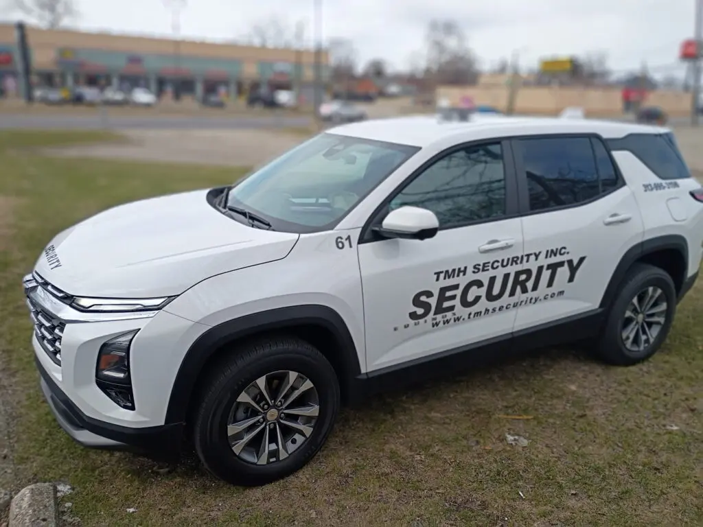 White security vehicle parked on grass with clear security markings.